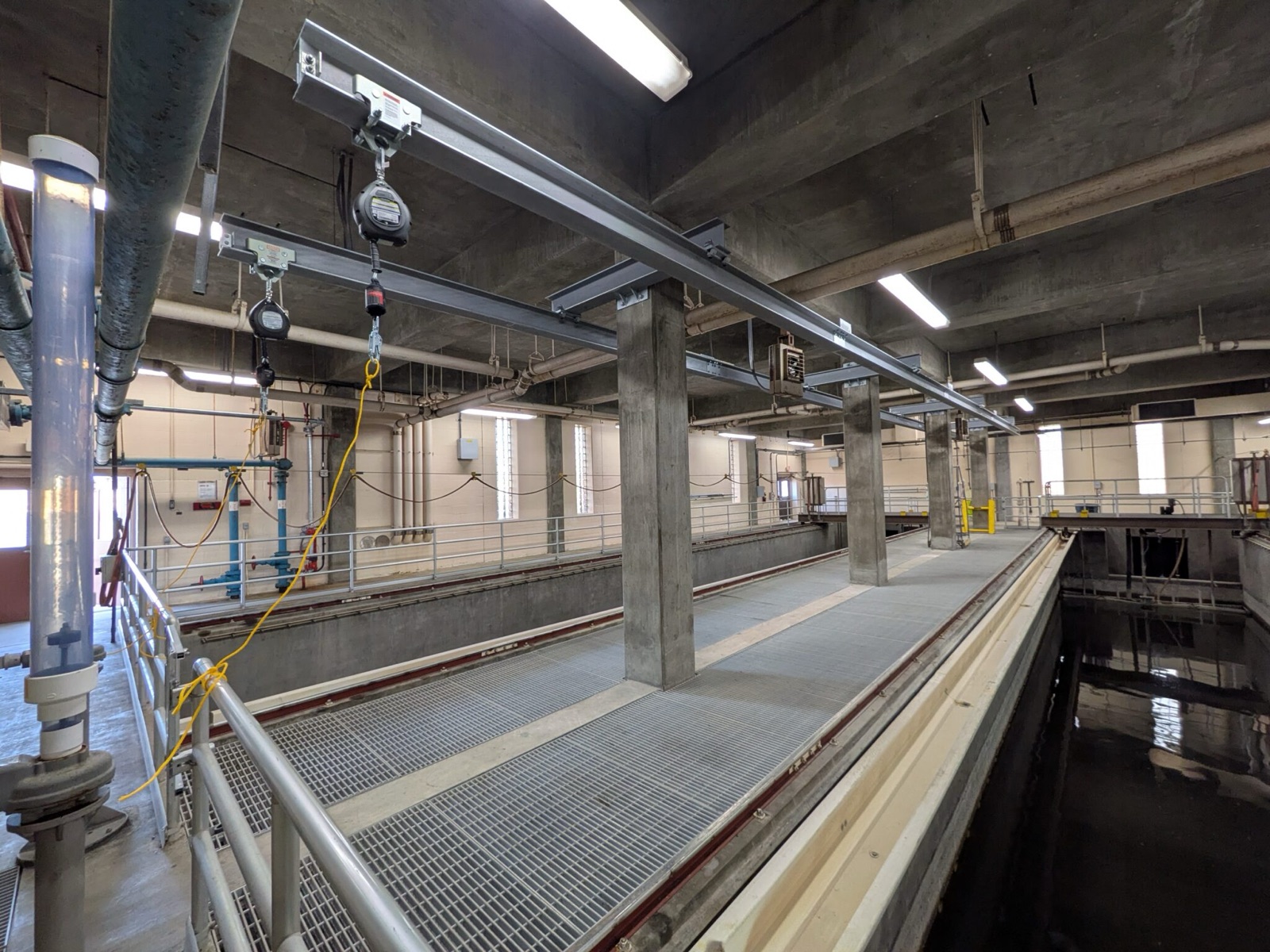 Ceiling-mounted overhead rigid rail and trolley running the length of an interior walkway