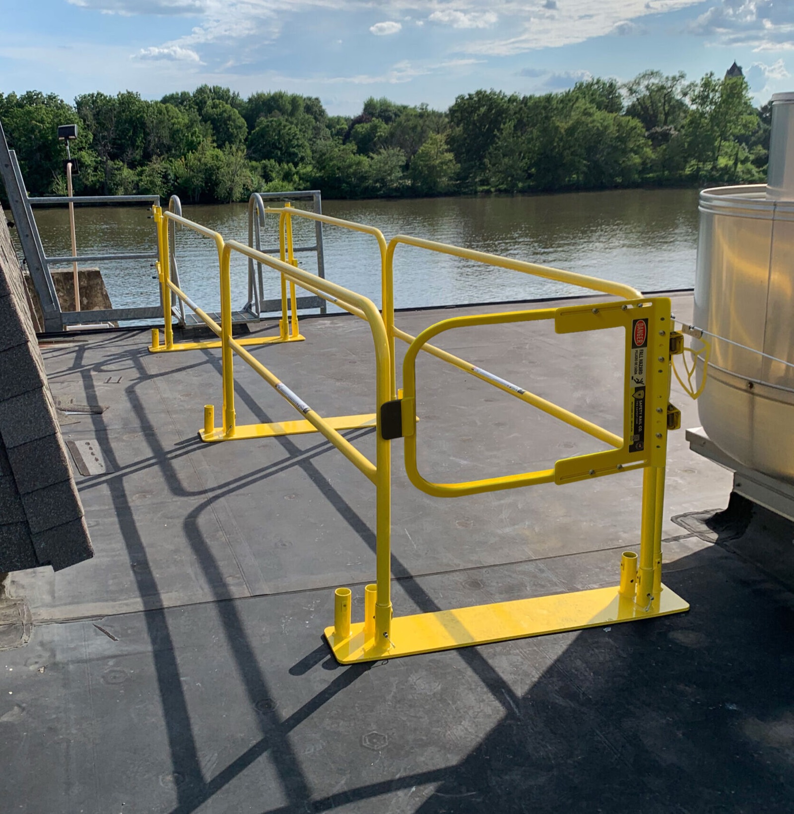 Yellow spring-loaded self-closing safety gate set in a run of guardrail