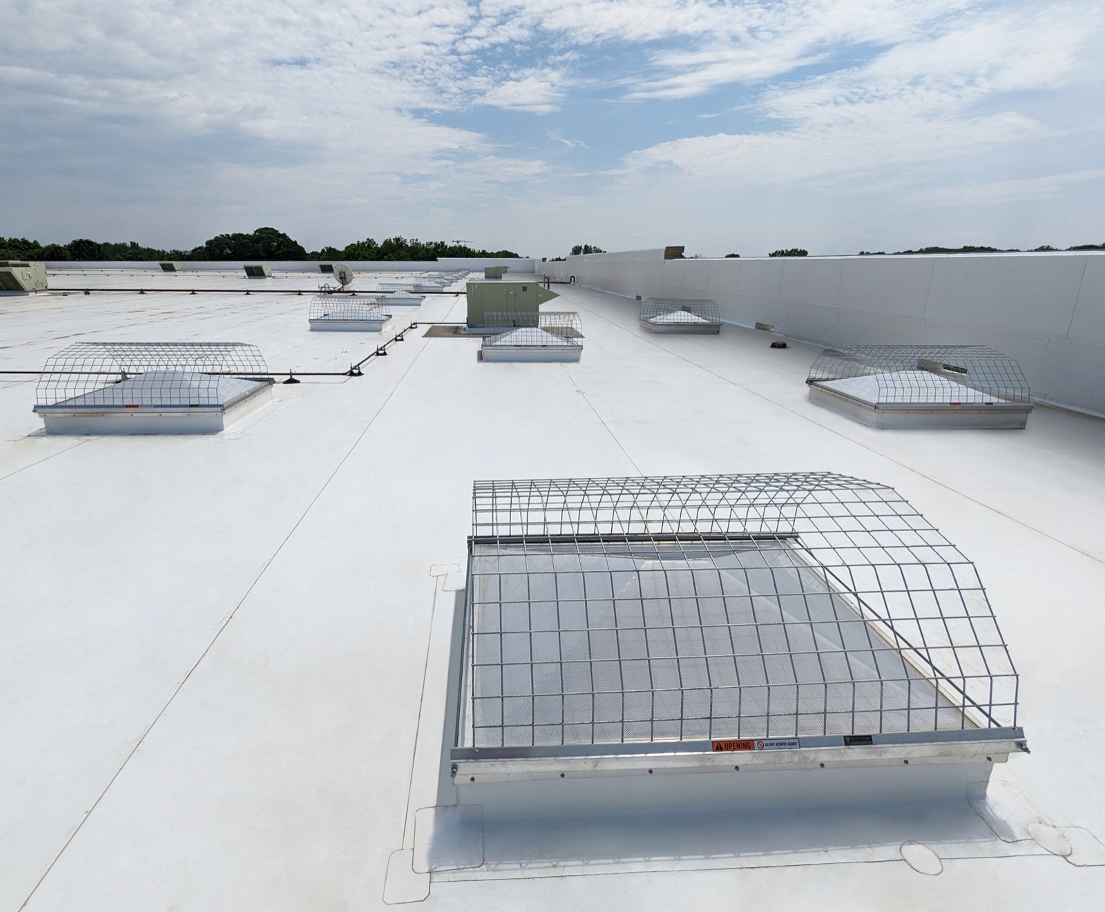 Wire-mesh screens caging a row of domed skylights across a white membrane roof